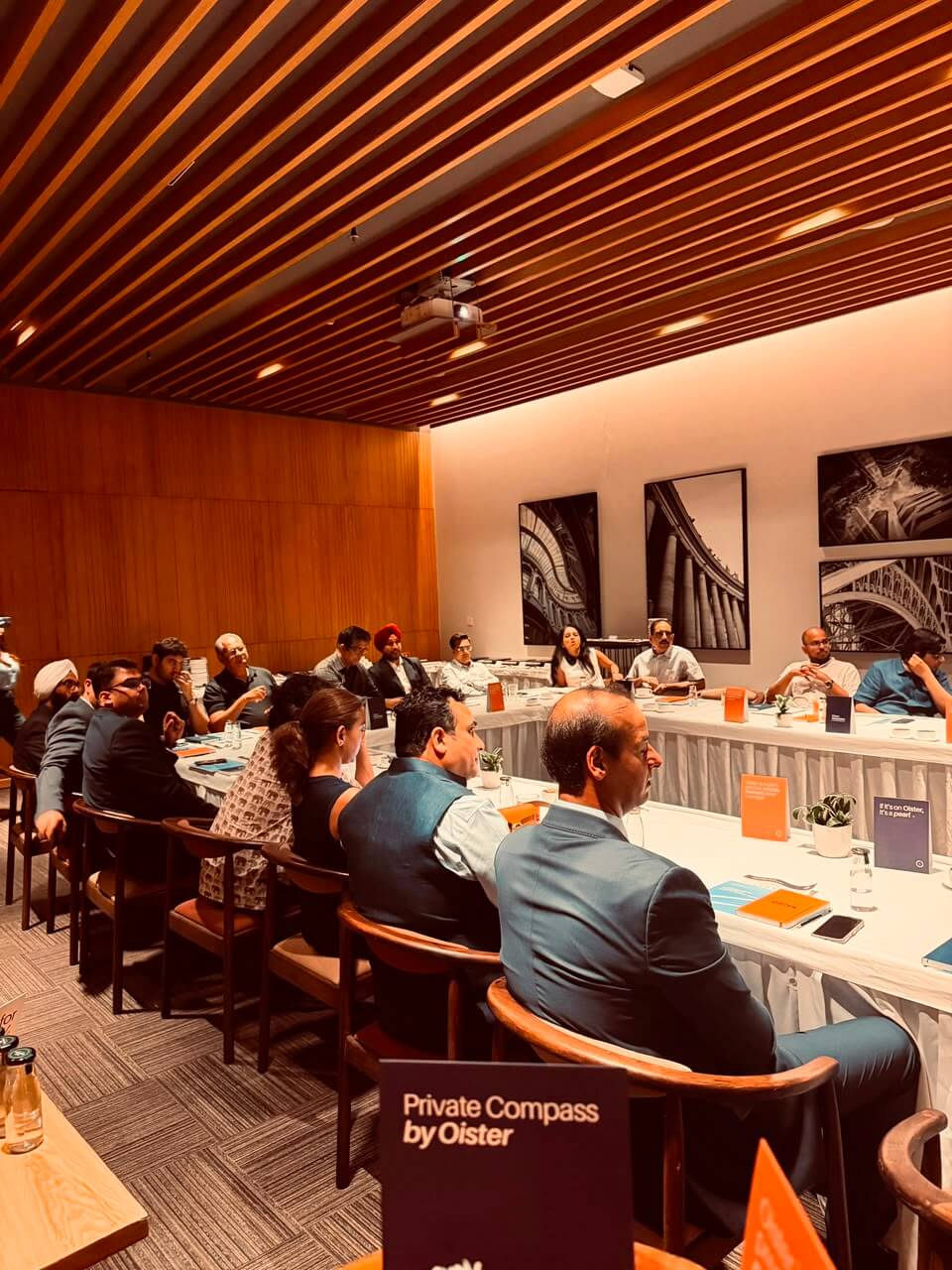Attendees seated at long tables with Private Compass by Oister signage.